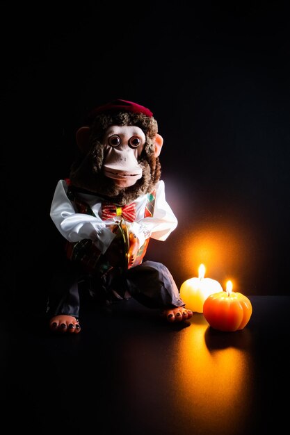 Photo retro toy monkey with cymbals jolly chimp and two candles in form of pumpkins in the darkness