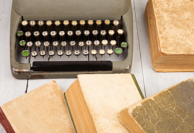 Retro typewriter and old vintage books on white wooden background