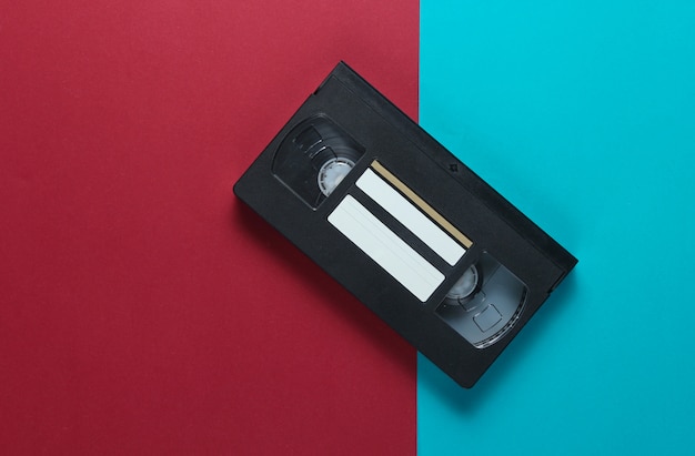 Retro videocassette op een rood-blauwe tafel. Bovenaanzicht