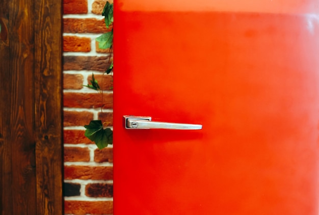 Retro vintage style red fridge against brick wall