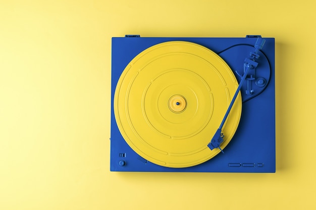 Retro vinyl record player in a stylish color scheme on a yellow background. retro music equipment.