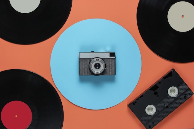 Retro vinyl record videocassette, filmcamera op een koraal kleur achtergrond met een blauwe cirkel. Bovenaanzicht