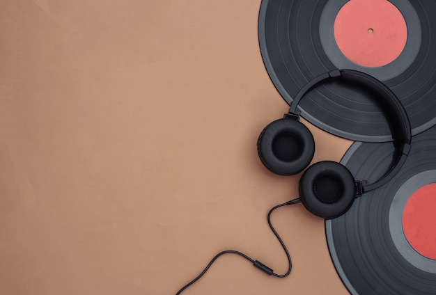 Retro vinyl records and stereo headphones on a brown background. Copy space. Top view. Flat lay