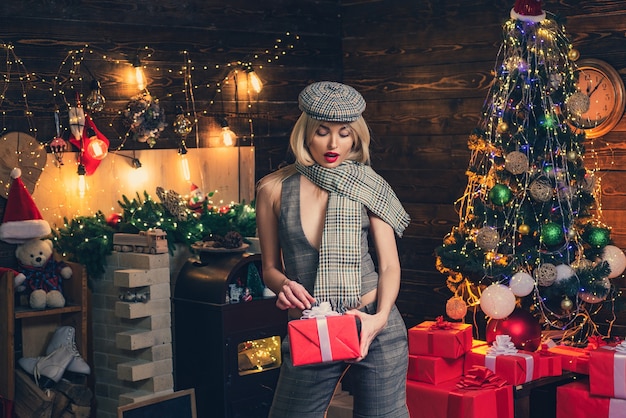 Retro donna con champagne sopra priorità bassa dell'albero di natale. ragazza di moda di bellezza con scatola regalo di natale.