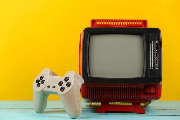 레트로 게임. 비디오 게임 경쟁. 노란색 배경에 게임패드가 있는 오래된 TV. 속성 80년대