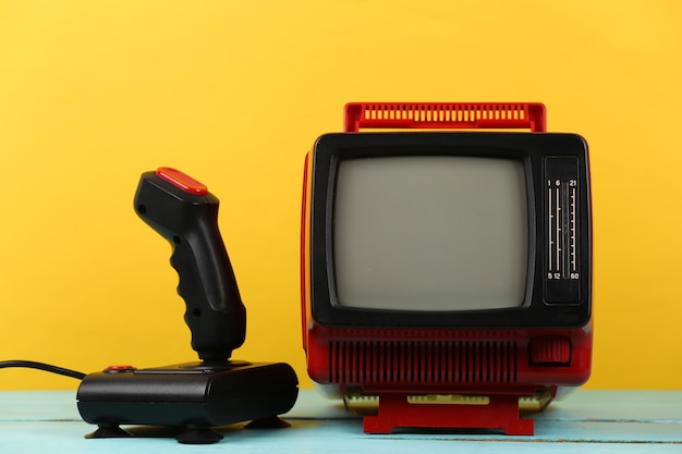 Retrogaming. video game competition. old tv with joystick on\
yellow background. attributes 80s