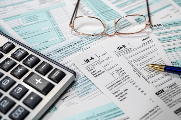 Restituzione dei moduli fiscali statunitensi 1040 con calcolatrice a penna e occhiali concetto finanziario aziendale concetto finanziario tempo di imposta