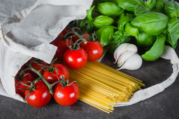 Photo reusable bag with groceries. tote bag, minimal waste. basil, tomatoes cherry, garlic in fabric bag