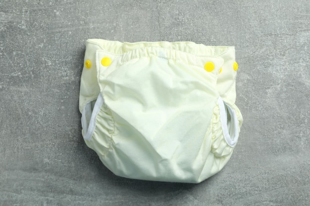 Photo reusable diapers on gray textured background, close up