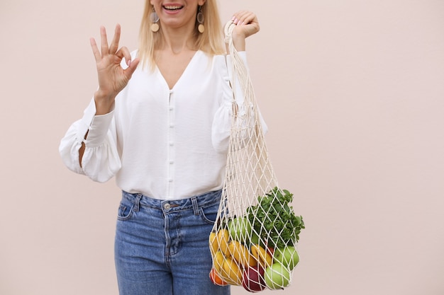 Reusable eco bag for shopping string shopping bag with fruits in the hands of a young woman zero