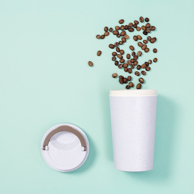 Reusable eco coffee cup and roasted coffee beans 