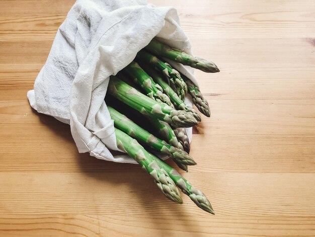 Borsa ecologica riutilizzabile con asparagi freschi su tavolo di legno concetto di acquisto di generi alimentari a zero rifiuti divieto di plastica scegli sacchetti di cotone biologico senza plastica per lo shopping