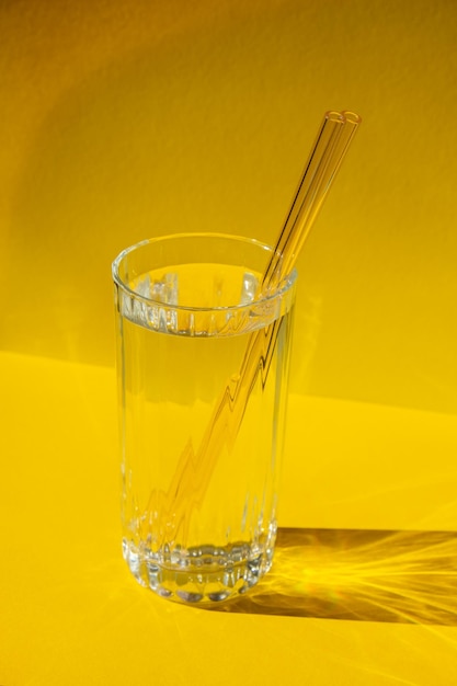 Reusable glass straws in glass with water on yellow background eco-friendly drinking straw set with