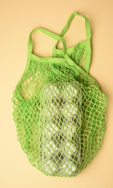 Reusable green textile shopping bag with egg cartons on a green background, zero waste