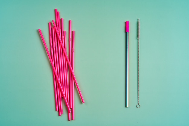 Photo reusable metal straw among pack of pink plastic beverage straws and cleaning tool