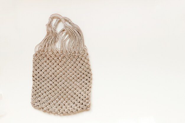 Photo reusable net bag or mesh shopper on beige background with copy space zero waste concept