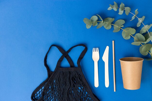 Reusable shopping bag and eucalyptus leaves on Blue background.