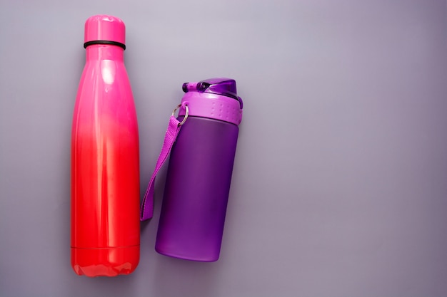 Reusable water bottles over grey table, drinking water.