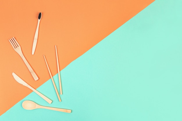 Reusable wooden cutlery and bamboo toothbrush. Eco friendly fork, knife, spoon on a mint orange background. Zero waste concept. Copyspace.