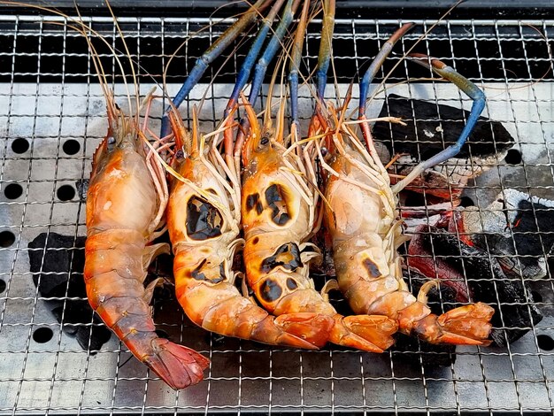 Reusachtige zoetwatergarnalen grillen op een vlammend houtskoolvuur en koken voedsel voor het feest