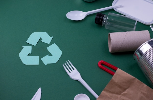 Reuse reduce recycle flat lay concept with plastic, paper, and polyethylene waste. Ecology wall image with recycling symbol.