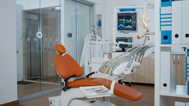 Revealing shot of orthodontic chair with nobody in teeth x ray images on modern display empty medica...