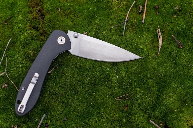 Reverse knife with a clip on the handle Knife in a bent position on the moss Top