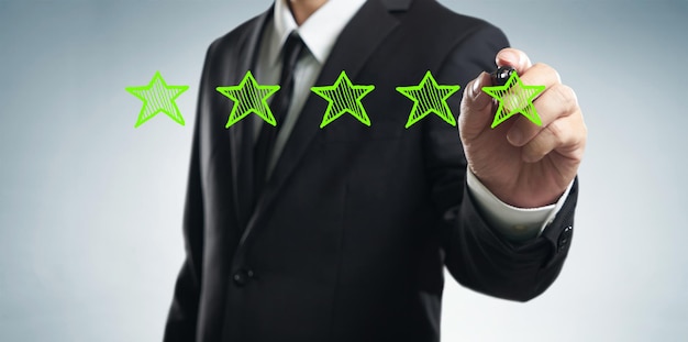 Foto revisione aumento della valutazione delle prestazioni e del concetto di classificazione l'uomo d'affari disegna cinque stelle verdi per aumentare la valutazione dello sfondo bianco della sua azienda