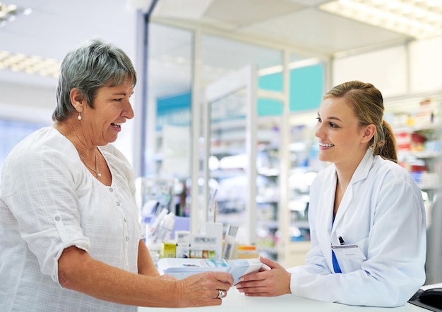 Photo reviewing the instructions with her customer shot of a young pharmacist assisting a customer