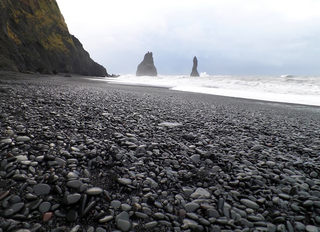 Pile di reynisdrangur e spiaggia di sabbia nera in una giornata ventosa, vik del sud dell'islanda