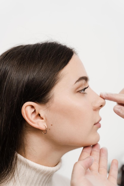 Foto la rinoplastica sta rimodellando la chirurgia del naso per cambiare l'aspetto del naso e migliorare la respirazione il medico orl sta toccando il naso e consultando la paziente in una clinica medica prima dell'intervento di settoplastica