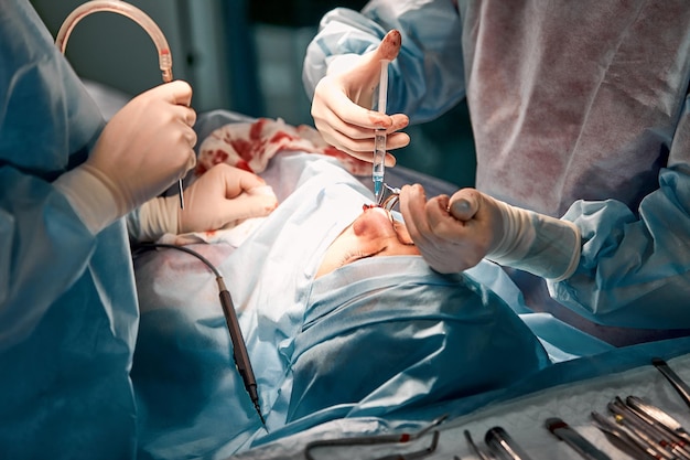 Rhinoplasty men, the surgeon's gloved hands hold the instruments during nose surgery. Doctor in gloves holds a medical instrument during rhinoplasty.