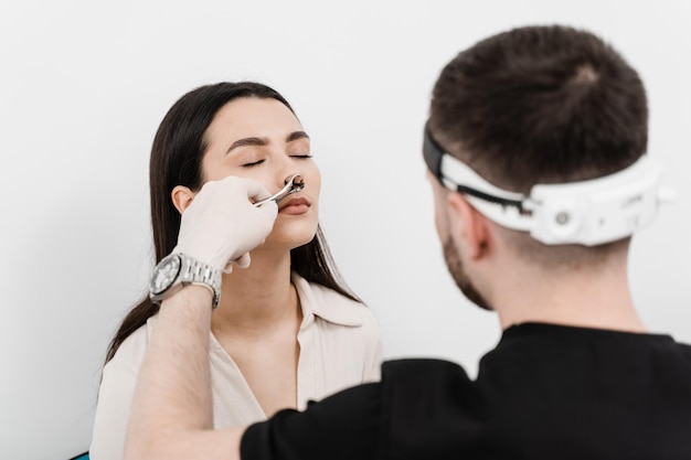 Rhinoscopy of woman nose Consultation with ENT doctor Otolaryngologist examines girl nose before procedure of endoscopy of nose