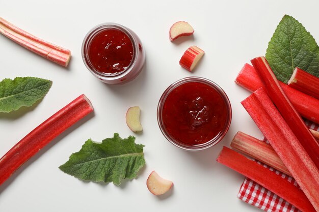 Rhubarb stalks jars of jam mint on white background flat lay