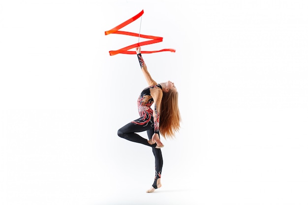 Rhythmic gymnastics. Young gymnast girl with red ribbon on white