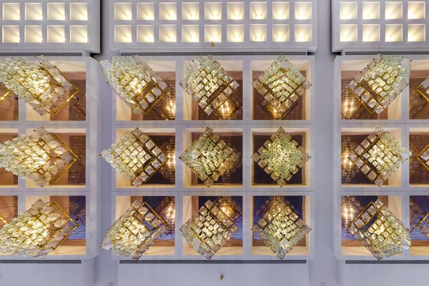 Rhythmic texture on suspended ceiling with rows of halogen\
spots lamps and drywall construction with chandelier stretch\
ceiling white and complex shape