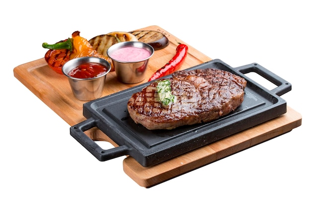 Rib eye steak on wooden tray with grilled vegetables on white background