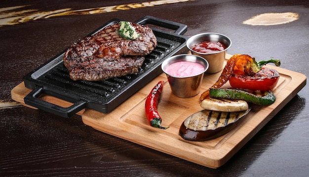 Rib eye steak on wooden tray with grilled vegetables