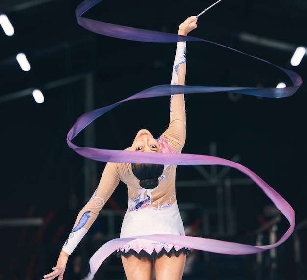 Foto ginnastica del nastro donna flessibile e danza in allenamento e competizione da dietro movimento ritmico del ballerino femminile e azione elegante di sport di talento creativo e evento concertistico