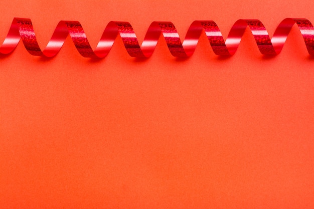 Ribbon of shiny red serpentine on a red background. Top view