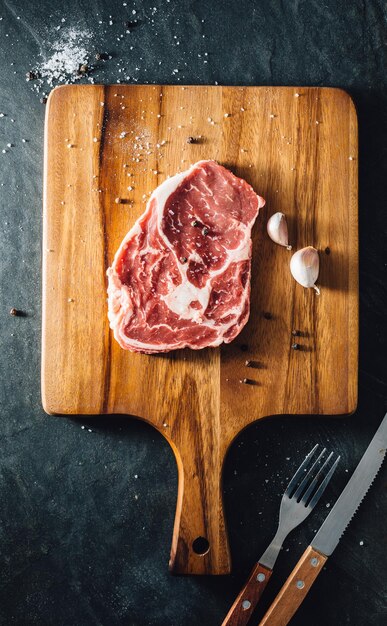 Foto ribeye steak met houten snijplank op stenen zwarte achtergrond