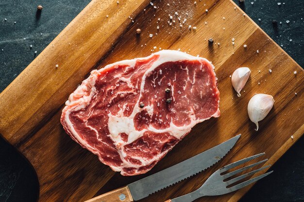 Ribeye steak met houten snijplank op stenen zwarte achtergrond