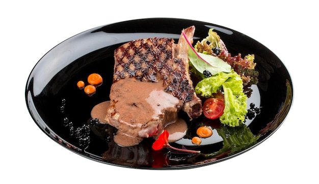 Ribeye steak with demiglace sauce on a glossy black plate