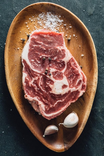 ribeye steak with wooden cutting board on stone black background