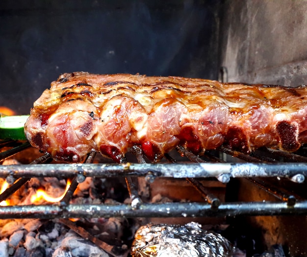 Ribs dipped in sauce over the embers on the barbecue