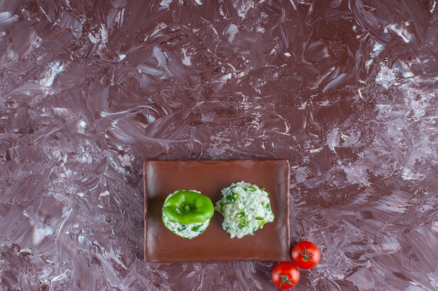 Rice and bell pepper on a platter next to tomatoes on the marble surface