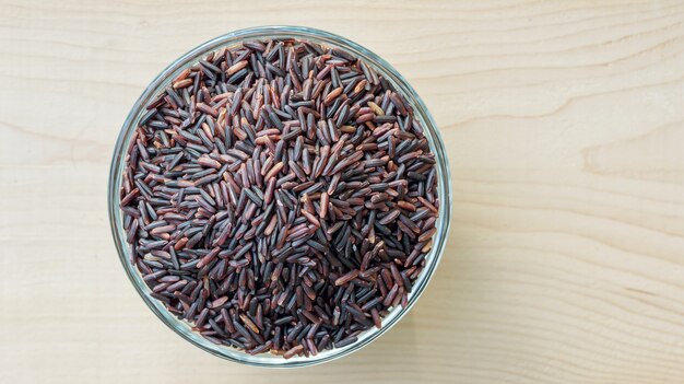 Rice berry in a bowl on a wooden background.