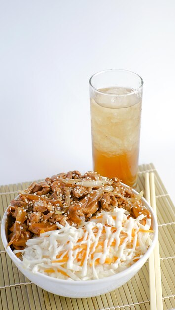 Rice bowl with sliced chicken and oyster sauce accompanied by a\
drink of iced tea