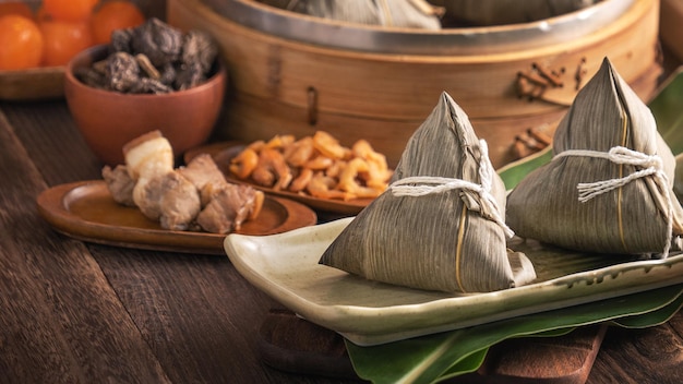 Rice dumpling Chinese zongzi food in a steamer on wooden table with red brick wall window background at home for Dragon Boat Festival concept close up