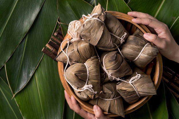 Rice dumpling zongzi traditional chinese food on green leaf\
background of dragon boat festival duanwu festival top view flat\
lay design concept